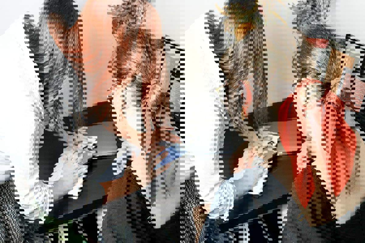 kvinnliga kollegor diskuterar och kollar på mobil